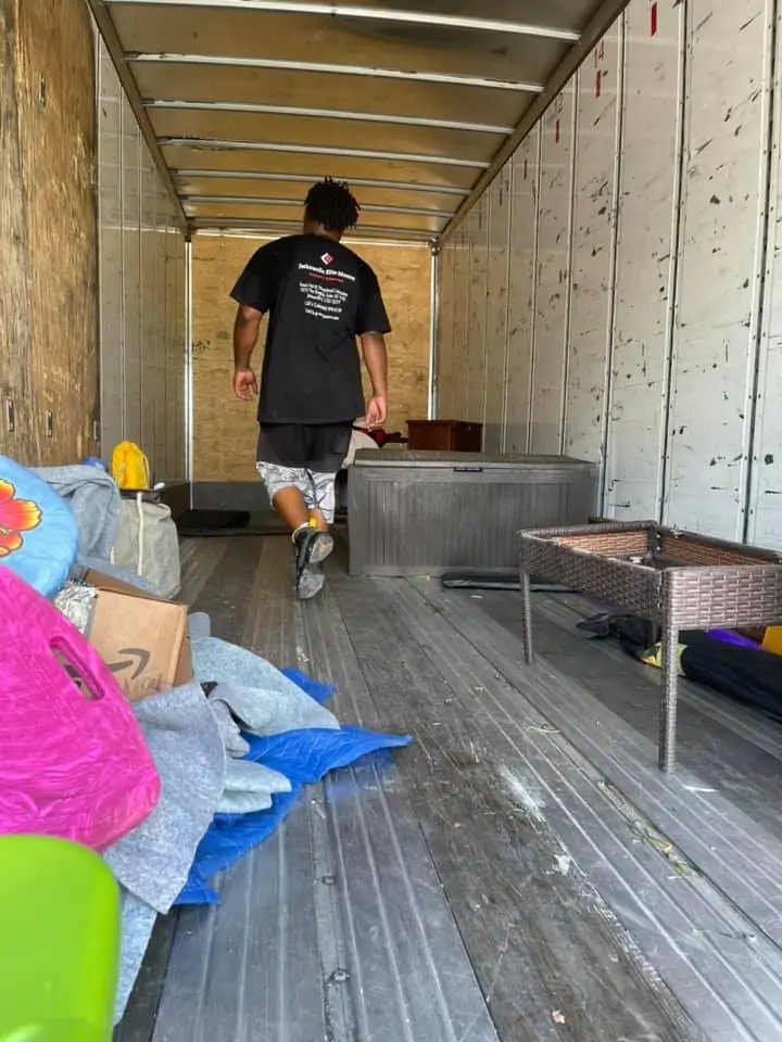 A Jacksonville Elite Movers crew member carrying furniture inside a moving truck